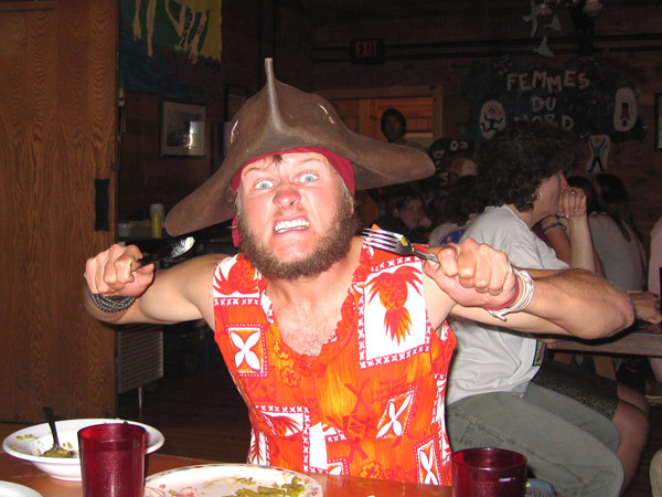 some freak in an orange dress and pirate hat eating dinner